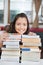 Schoolgirl Leaning On Stack Of Books In Classroom