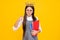 Schoolgirl nerd princess in school uniform and crown celebrating victory on yellow background. School child hold book