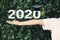 Schoolgirl outstretched arms with Class of 2020 with graduation cap on green nature background