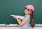 Schoolgirl with paper plane play near a blackboard, empty space, education concept