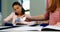 Schoolgirl passing chit to her classmate during exam in classroom