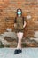 Schoolgirl poses against a brick wall in the backyard of the school, wearing a protective mask on her face from a coronavirus