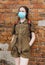 Schoolgirl poses against a brick wall in the backyard of the school, wearing a protective mask on her face from a coronavirus