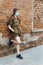 Schoolgirl poses against a brick wall in the backyard of the school, wearing a protective mask on her face from a coronavirus