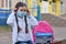 The schoolgirl puts on a mask to prevent colds and viruses. Medical concept.Back to school. Child going school after pandemic over