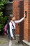 Schoolgirl with rucksack ringing in doorbell