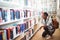 Schoolgirl selecting book from book shelf in library