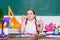 Schoolgirl sit desk chalkboard background. Kid student in school. Girl small child eating apple snack. School break