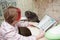 Schoolgirl sits at the table, teaches lessons. On the table, next to it, sits a fold-eared Scots cat