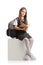 Schoolgirl sitting on a white cube and reading a book