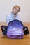 Schoolgirl speaks on a smartphone. Schoolgirl with a backpack sits on the floor and talks on the phone. vertical photo