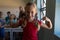 Schoolgirl standing flexing her bicep muscles in an elementary school classroom