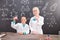 Schoolgirl and successful teacher of chemistry in whitecoats holding tubes