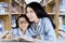 Schoolgirl and teacher smiling in the library