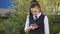 Schoolgirl teen reads the message on the smartphone near the school building.