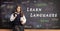 Schoolgirl in a uniform with books standing in front of a blackboard with text learn languages