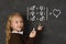 Schoolgirl in uniform holding chalk writing on blackboard standing for freedom of sexuality orientation