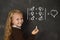 Schoolgirl in uniform holding chalk writing on blackboard standing for freedom of sexuality orientation