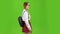Schoolgirl walks with a backpack on her shoulders and waves her hand. Green screen. Side view