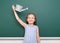 Schoolgirl with watering can play near a blackboard, empty space, education concept