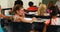 Schoolgirl whispering into her friends ear in classroom