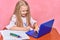 Schoolgirl writes lessons in notebook. online learning for laptop