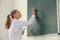 Schoolgirl writing chemistry formula on blackboard