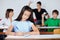 Schoolgirl Writing At Desk While Classmates