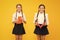 Schoolgirls study together on yellow background. Study language. Cute children study with textbook. Practice and improve