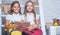 Schoolgirls studying homework during her lesson at home. Story reading in book at two small girls. Learning and