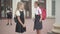 Schoolgirls talking before lessons as blurred boy standing with football ball at the background. Schoolchildren