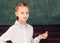 Schoolkid is doing his math homework in classroom at school. Pupil writing something on blackboard in the classroom