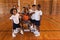 Schoolkids and basketball coach forming hand stack and looking at camera in basketball court