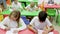 schoolkids drawing with cheerful female teacher at classroom