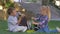 Schoolkids eat sandwiches and drink the juice from the bottles during lunch time sitting on grass in schoolyard