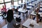 Schoolkids raising hands while sitting at desk in classroom