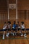 Schoolkids talking with each other and sitting on bench at basketball court