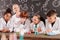 Schoolkids watching different reactions in glass tubes with chemical compounds