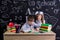 Schoolkids working at the desk with books, school supplies. Left-handed boy writing the text and smiling girl looking at