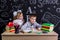 Schoolkids working at the desk with books, school supplies. Left-handed boy writing the text and smiling girl standing