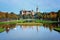 Schweriner castle seen from the park with water canals, reflections, sculptures and trees with colored foliage on a sunny autumn