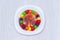 Science experiment for kids. Circle of colored candies on white plate