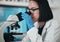 Science, microscope and Asian woman in laboratory with safety glasses for research, analysis and study. Microbiology