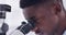 Science, microscope and face with man in laboratory for experiment, vaccine and healthcare. Analysis, medical and