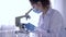 Scientific laboratory, women with microscope doing chemical examination in biological study under sterile conditions