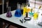 Scientific tools on the table, the blue, yellow, and purple chemical glass flasks stood out, their colors enhanced by the soft