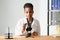 Scientific young woman looking at you while working at laboratory with a microscope.