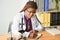 Scientific young woman looking at you while working at laboratory with a microscope.