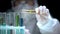 Scientist adding liquid from test tube with warning symbol, dangerous research