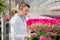 A scientist biologist woman in a white coat cares and tests the flowers in the greenhouse.